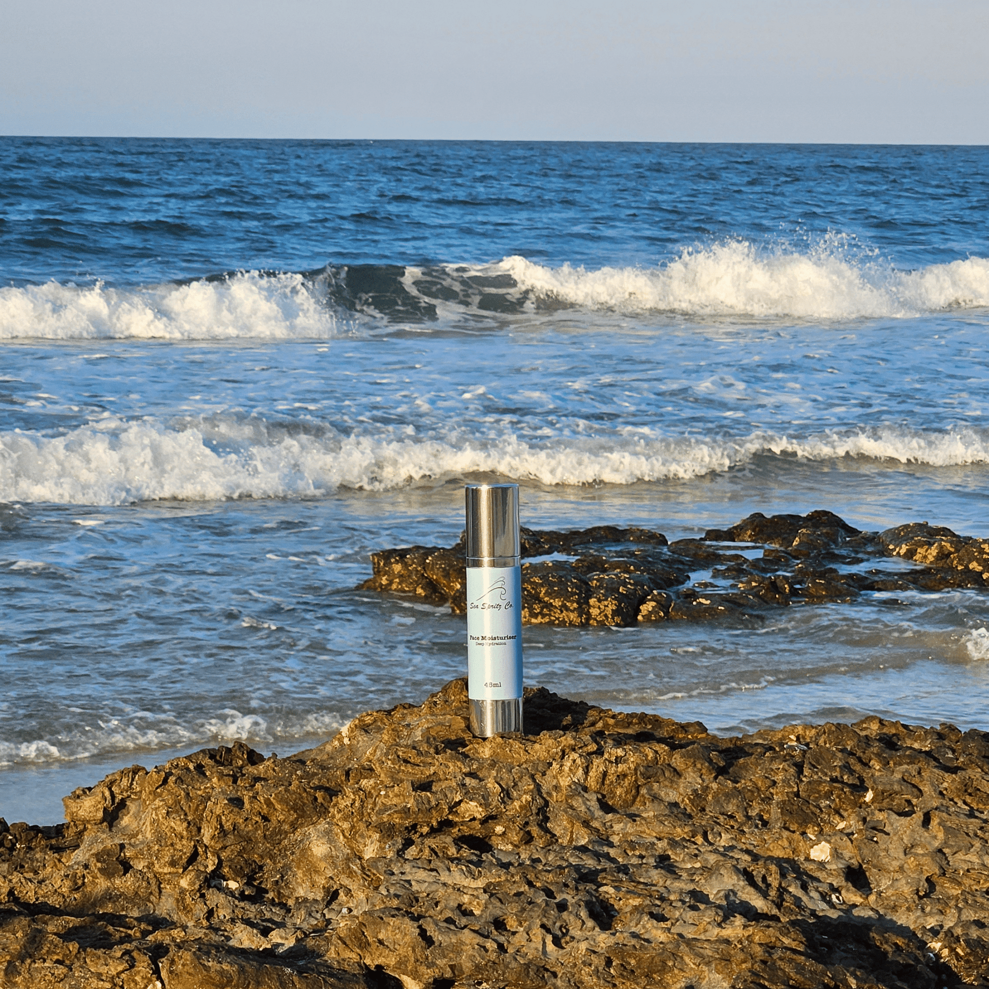 Photo of Face Moisturiser product bottle in front of the ocean